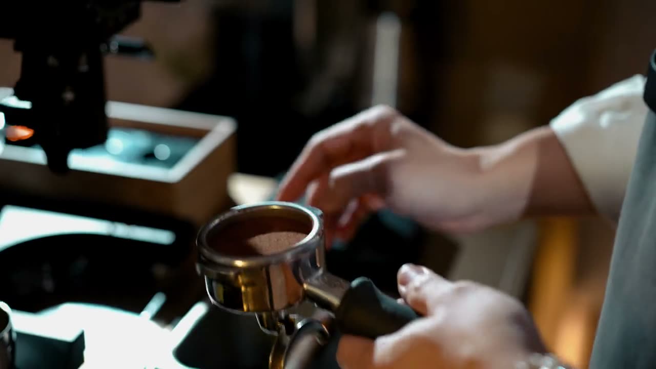 A barista pulling a shot: ground coffee tamped into the portafilter under the group head.