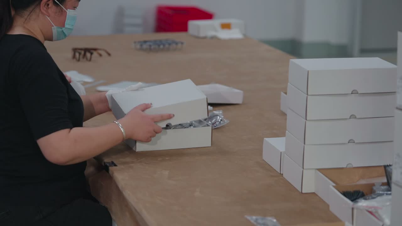 A worker packs finished frames into white boxes.