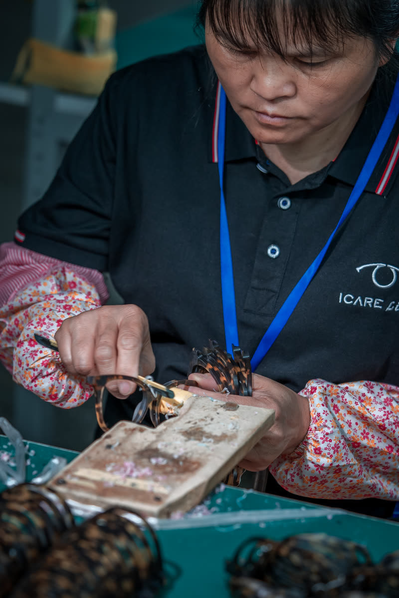 A technician works a frame over a torch at the bench.