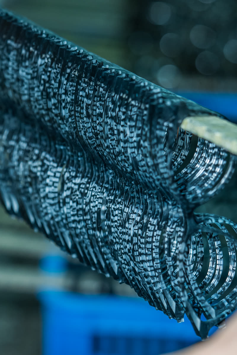 A dense rack of wire fronts clamped in a jig, seen end on.