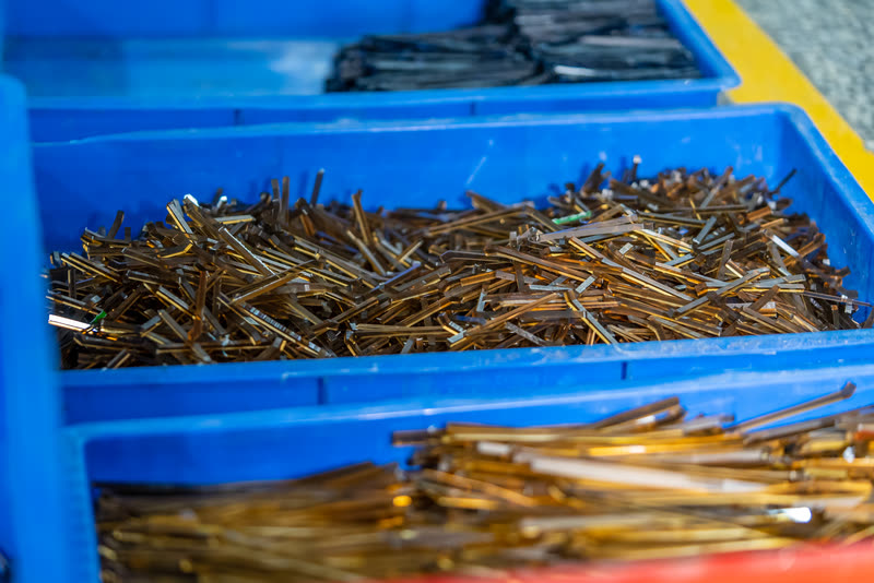 A blue crate filled with brass temple arms.