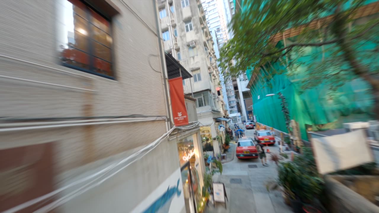 A drone flying fast down a Hong Kong street, buildings blurred on both sides.