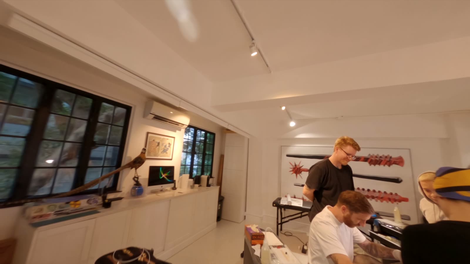 The Star Crossed studio: a bright white room with framed artwork, artists working at tables.