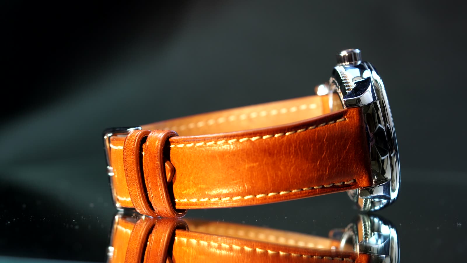 A Von Vogel watch on a tan leather strap, standing on a black reflective surface.